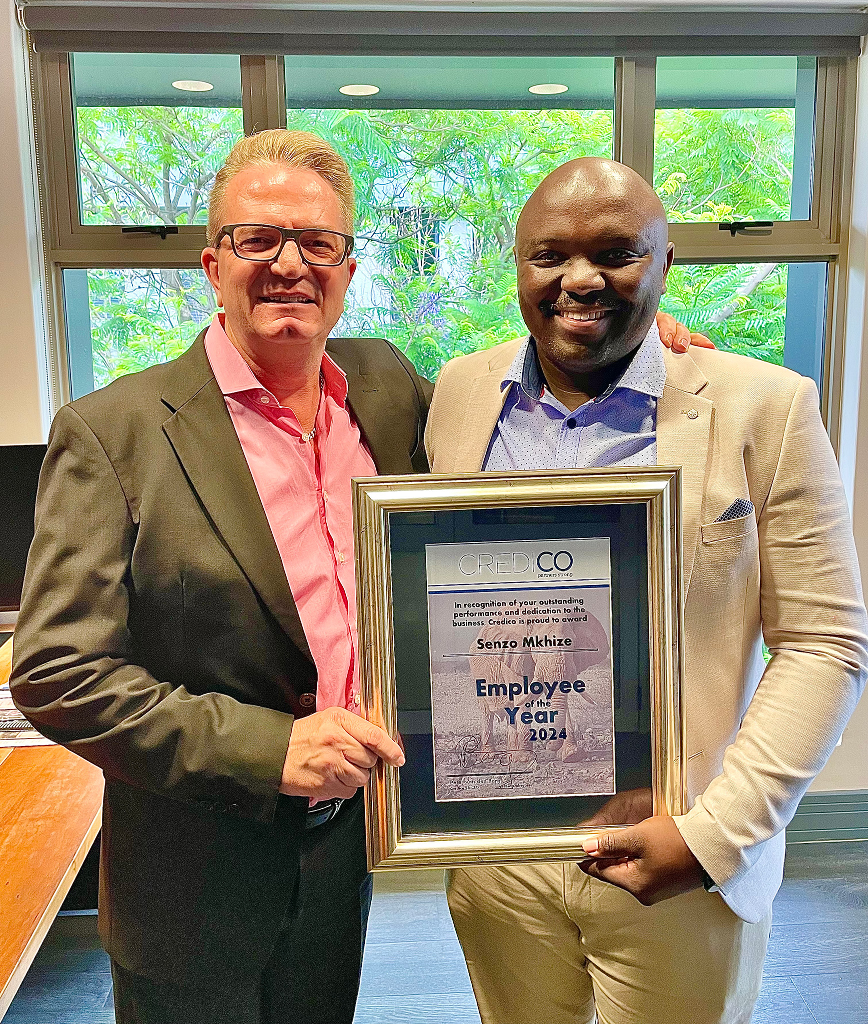 Credico South Africa's Employee of the Year for 2024, Senzo Mkhize, right, holds a framed certificate of recognition alongside Credico South Africa's CEO Peter van den Berg, left.