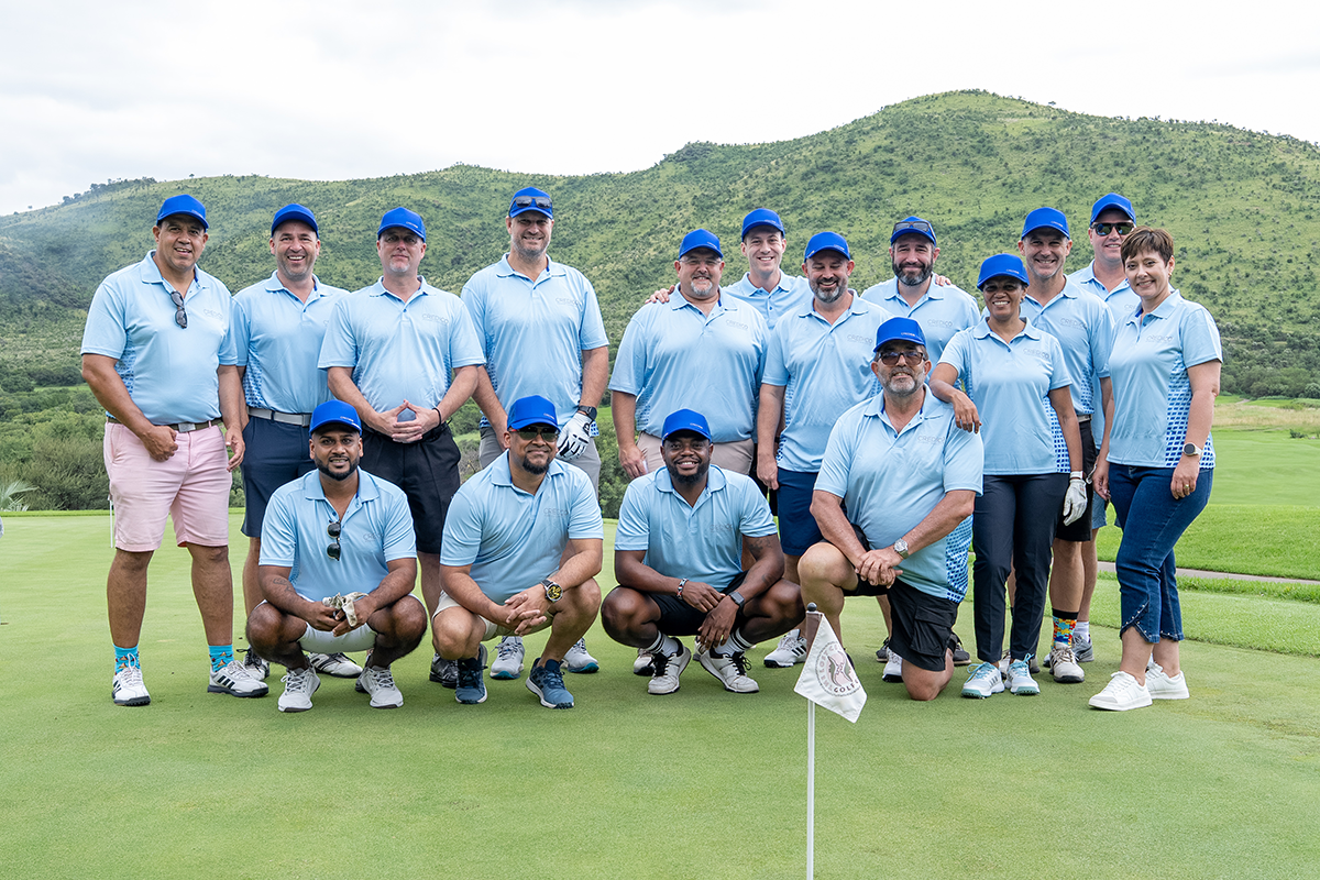Credico SA team members and clients pose for a group photo in matching light blue golf shirts and blue caps on the green at the Lost City golf course at Sun City Resort before the 2025 Awards Gala.