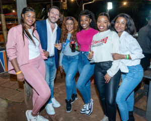 A group of business owners poses for a group photo with Jesse Young during a dinner at the Shebeen prior to the South Africa Awards Gala in March 2025