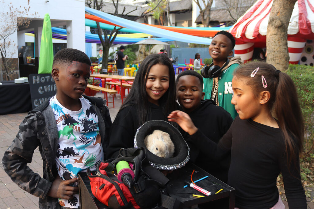a group of children gather around a rabbit in a magician's hat at Credico South Africa's 2025 Christmas in July