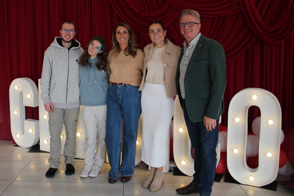 A smiling group of five people pose in front of a lighted Credico sign at Credico South Africa's 2025 Christmas in July