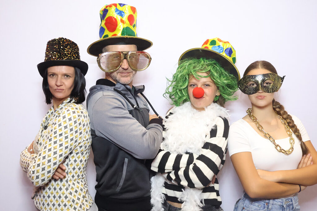 Four people pose in a photobooth with costumes, hats, and wigs at Credico South Africa's 2025 Christmas in July