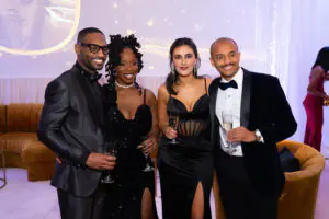 Four attendees in tuxedos and formal gowns pose for a photo during the champagne reception at the 2026 Limitless Kickoff Gala