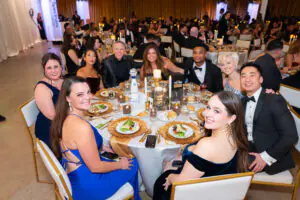 a full table of formally-dressed attendees turns to smile for the camera at the 2026 Limitless Kickoff Gala