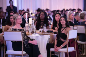 A table of formal diners seated around a sparkling gold-adorned table watch the awards presentation at the 2026 Limitless Kickoff Gala