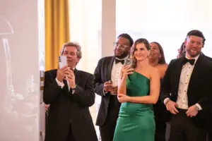 Friends and family of new National Consultant Matthew Goodchild stand to the side of the stage to take videos and photos of him during the 2026 Limitless Kickoff Gala