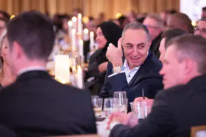 Seated around a table set with sparkling gold and candles, Credico founder and chairman Antoine Nohra gives a thumbs-up to Credico President Jesse Young during the 2026 Limitless Kickoff Gala