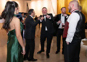 New board member James Sagar grins and points at the camera from the center of a group conversation during the 2026 Limitless Kickoff Gala