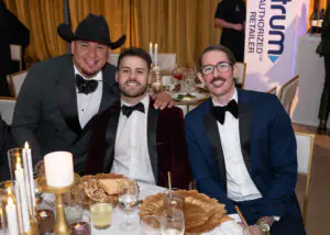 Three tuxedoed attendees smile from their table during the 2026 Limitless Kickoff Gala