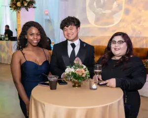Three business owners look up from their conversation around a gold-draped cocktail table during the 2026 Limitless Kickoff Gala