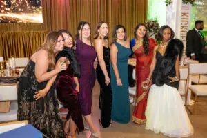 A row of happily smiling women in formal gowns pose for a photo at the 2026 Limitless Kickoff Gala